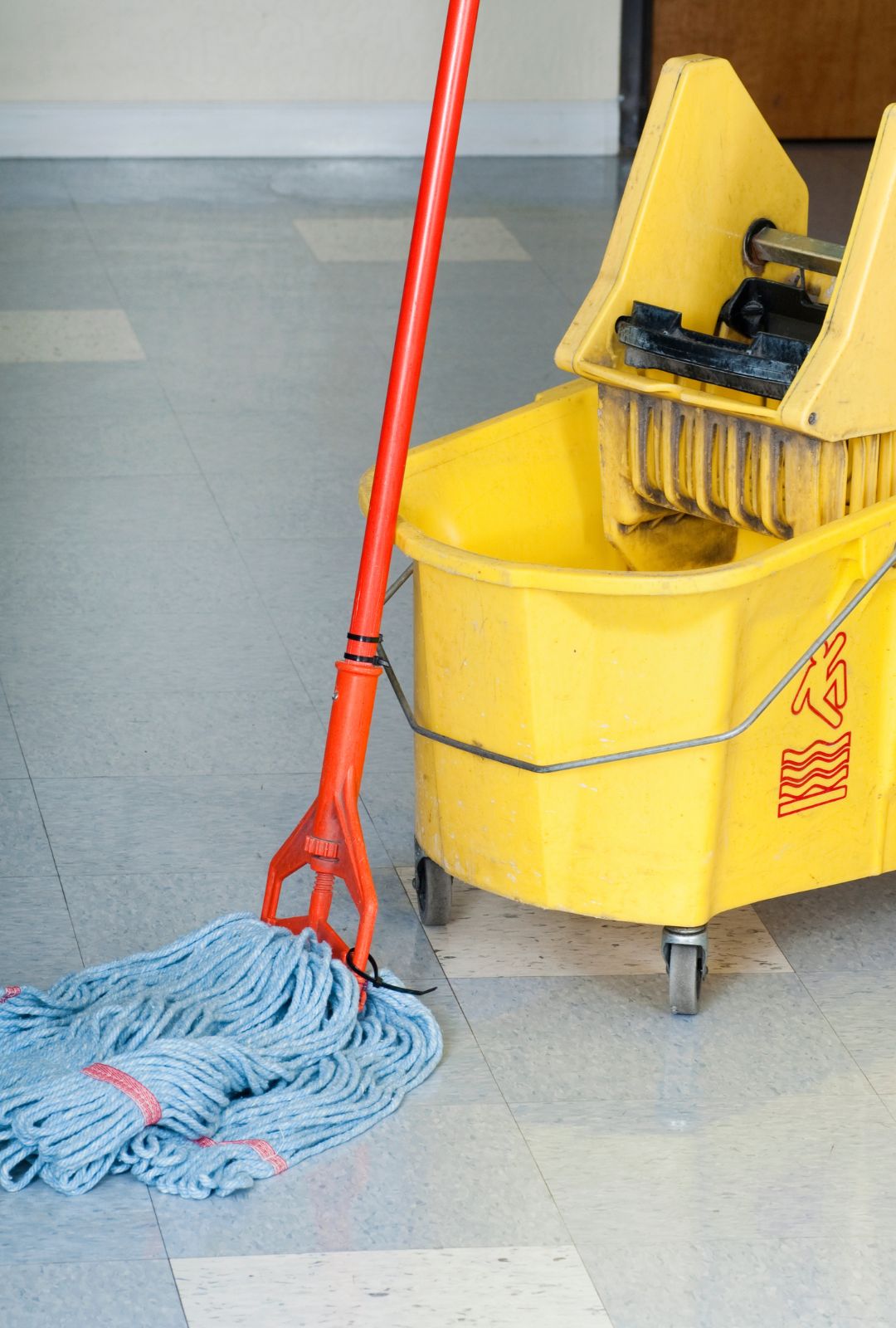 Uniformed janitor mopping a corporate office corridor during a scheduled janitorial services visit
